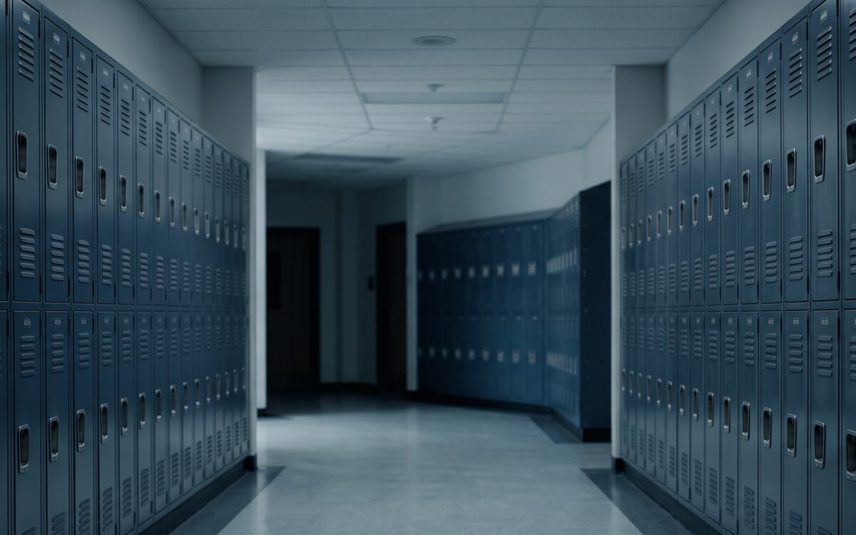 An empty school hallway lined on both sides with rows of metal lockers